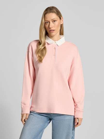 Frauenmodel trägt Longsleeve mit Polokragen und kurzer Knopfleiste von Gant, rosa Baumwoll-Mix, Loose Fit, Ganzkörperansicht von vorne.
