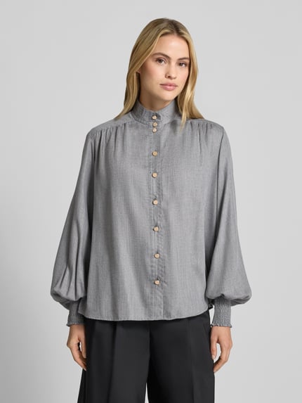 Vrouwenmodel draagt Relaxed Fit Hemdbluse aus Viskose-Mix Model 'DUNIA' van 0039 Italy, grijs, opstaande kraag, Smokdetail, langemouwen, geheel effen oppervlak, Ruglengte maat S 64 cm, Mouwlengte maat S 67 cm, frontaal bovenlichaam close-up.