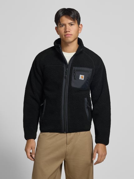 Männermodel trägt Teddyjacke mit Brusttasche Modell 'PRENTIS LINER' von Carhartt Work In Progress in Schwarz, Reißverschluss, Label-Patch, Ganzkörperansicht von vorne, Herrenjacke Regular Fit.