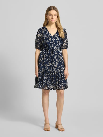 Frauenmodel trägt Knielanges Kleid mit Kordelzug an der Taille von Apricot, Dunkelblau mit Blattmuster, Taillierter Schnitt, Knielänge, V-Ausschnitt, Elastische Ärmelabschlüsse, 1/2-Arm, Volantsaum, Rückenlänge bei Größe S: 93 cm, Brustweite 43 cm, Ärmellänge 30 cm, Ganzkörperansicht von vorne.