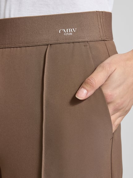 Vrouwenmodel draagt Straight fit stoffen broek met siernaad model 'Cameron' van Cambio, logoprint, elastische band, detailopname. Dames stoffen broek, verkorte pasvorm, achterzakken, bandwijdte maat 36: 39 cm, binnenbeenlengte maat 36: 67 cm.