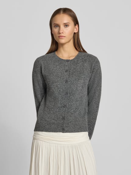 Frauenmodell trägt Regular Fit Strickjacke mit Lammwoll-Anteil von REVIEW, grau, gerippte Abschlüsse, Knopfleiste, Ganzkörperansicht von vorne.