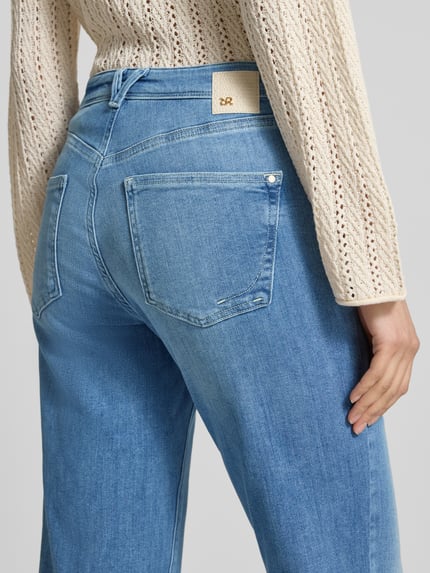 Vrouwenmodel draagt Flared fit jeans uit katoenmix model 'NELLA' van Raffaello Rossi, lichtblauw met steekzakken, detailopname rugaanzicht.