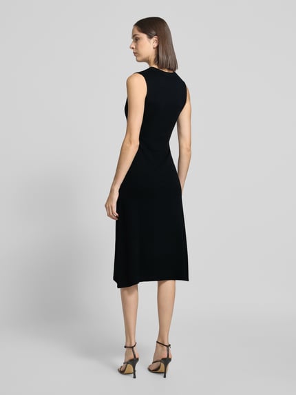 Frauenmodel trägt schwarzes Strickkleid mit Wasserfall-Ausschnitt Modell 'SANTA' von MANGO, Midikleid, Rückansicht, Ganzkörperansicht.