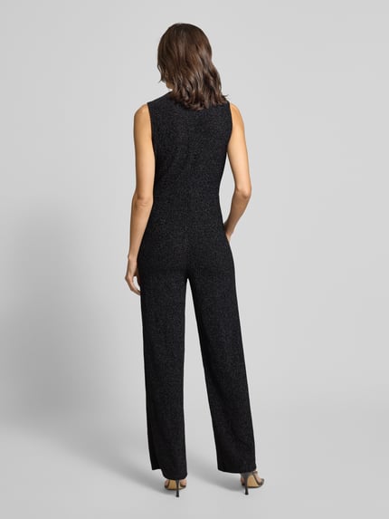 Modelka kobieca nosi szimmernder Jumpsuit mit V-Ausschnitt od Rich & Royal, czarny, lekko połyskujący, tkanina ze stretchem, widok całej sylwetki od tyłu. Regular Fit, pasek, długość 150 cm, długość nogawki 89 cm, szerokość w biuście 39 cm, długość tyłu 74 cm.