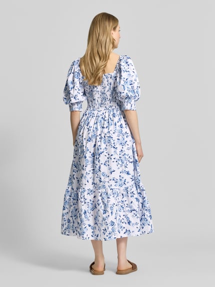 Vrouwenmodel draagt 'Midikleid mit Karree-Ausschnitt und Puffärmeln' van Apricot, blauw-witte A-lijn, all-over bloemenprint, katoen-elastaanmix, ruglengte 110 cm, borstwijdte 31 cm, mouwlengte 37 cm. Volledige lichaamsweergave achterkant.