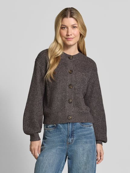 Kobieta prezentuje kardigan rozpinany Loose Fit Strickjacke mit einreihiger Knopfleiste model 'LEA' von VERO MODA, ciemnoszary, tekstura prążkowana, Ganzkörperansicht von vorne.