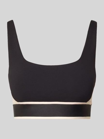 Produktfoto, schwarzer Slim Fit Sport BH mit Logo-Detail von Fabletics, elastischer Bund, verstellbare Träger, glatte Textur, beige Akzente
