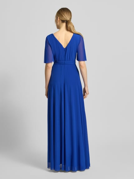 Frauenmodel trägt Abendkleid mit V-Ausschnitt und Schmetterlingsärmeln von Christian Berg Cocktail in leuchtendem Blau, Chiffon, Maxikleid, Wickel-Optik, taillierter Schnitt, fließende Textur, Rückseitiger Haken- und Reißverschluss, Ganzkörperansicht Rückansicht