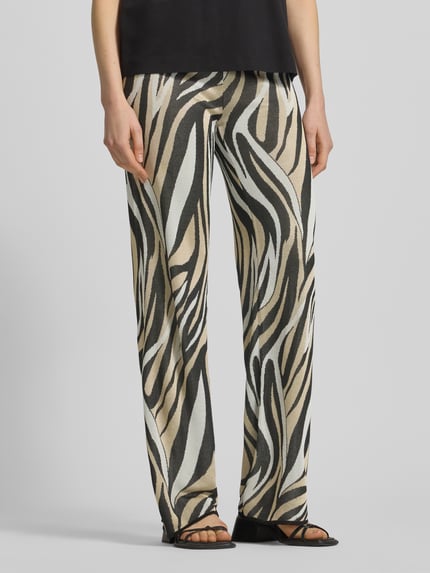 Kobiece modelka nosi spodnie z szerokimi nogawkami z wiskozy we wzór na całej powierzchni Hose aus Viskose im Allover-Look od Marella, beżowo-czarno-białe, elastyczny pas, szerokość w rozmiarze S: 36 cm, długość wewnętrzna nogawki w rozmiarze S: 84 cm, widok z przodu, zdjęcie w zbliżeniu na nogi.