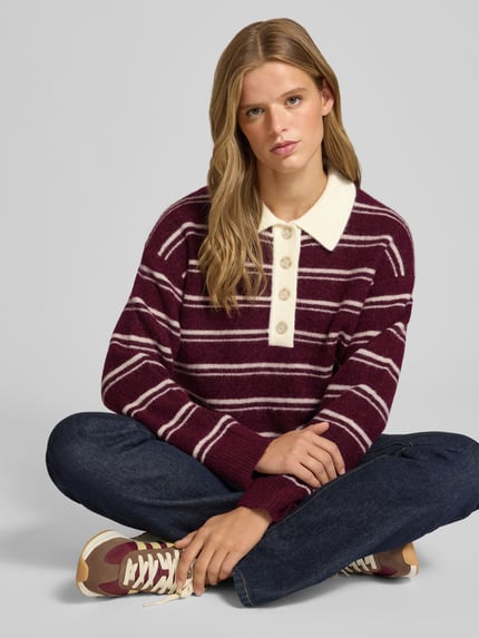 Modelka nosi Oversized Pullover aus Alpaka-Woll-Mix od Marc O'Polo DENIM, bordowe i białe paski, gładka tekstura, widok całej sylwetki z przodu.