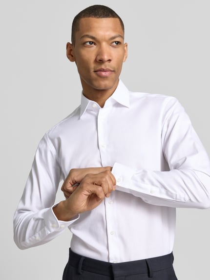 Mannelijk model draagt Regular Fit Business-Hemd met kentkraag van Christian Berg Men, puur katoen, knoopsluiting, sportmanchet, afgeronde zoom, ruglengte maat 39/40 78 cm, schouderbreedte 43 cm, mouwlengte 65 cm, nahaufnahme bovenlichaam.