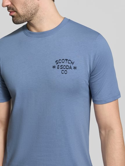 Männermodel trägt T-Shirt mit Rundhalsausschnitt von Scotch & Soda in Blau, Reine Baumwolle, Regular-Fit, Label-Print, Nahaufnahme Oberkörper.