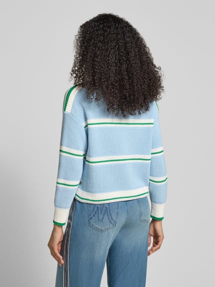 Kobiece modelka nosi Strickpullover mit U-Boot-Ausschnitt od Marc Cain w odcieniach niebieskiego i bieli, krój regular fit, mieszanka bawełny, prążkowana tekstura, luźne ramiona, widok całej sylwetki od tyłu.