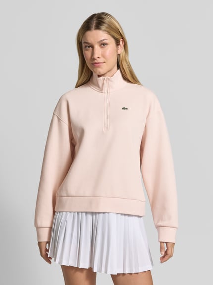 Frauenmodel trägt Relaxed Fit Troyer aus Baumwoll-Mix von Lacoste in zartem Rosa, glatte Textur, Damen Sweatshirt, Ganzkörperansicht von vorne.