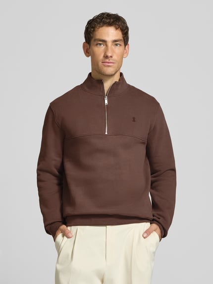 Männermodel trägt Regular Fit Troyer aus reiner Baumwolle Modell 'WAARLO FLEECE' von ARMEDANGELS in Braun, glatte Oberfläche, Ganzkörperansicht von vorne.