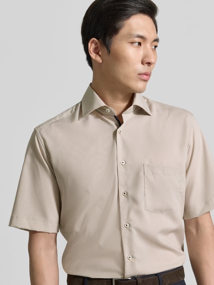 Männermodel trägt Regular Fit Freizeithemd aus Lyocell-Mix von ETERNA in Beige mit Kentkragen, Knopfleiste, Brusttasche, Nahaufnahme Oberkörper. Kontext: Herren Freizeithemd, Lyocell-Mix mit Baumwoll-Anteil, Regular Fit, Kentkragen, durchgängige Knopfleiste, kurzärmeliges Design, Brusttasche, Rückenlänge bei Größe 40: 81 cm, Schulterbreite bei Größe 40: 46 cm, Ärmellänge bei Größe 40: 28 cm.