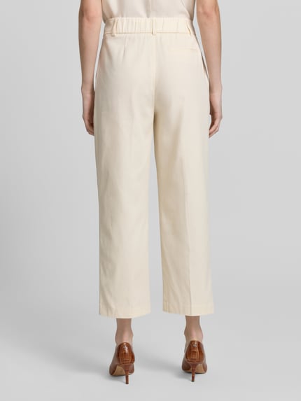 Frauenmodel trägt Cropped Hose mit Bügelfalten Modell 'Cisan Flow' von Someday aus Baumwoll-Elasthan-Mix in Beige, Ganzkörperansicht Rückansicht. Damen Hose, Bundweite 43 cm, Innenbeinlänge 67 cm bei Größe 36.