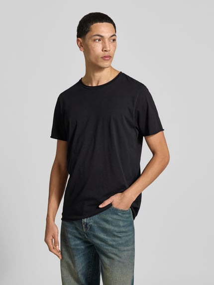 Męski model nosi T-Shirt mit Rollsaum od Filippa K, czarna bawełna, prosty krój, okrągły dekolt, długość tyłu 70 cm, Ganzkörperansicht von vorne.