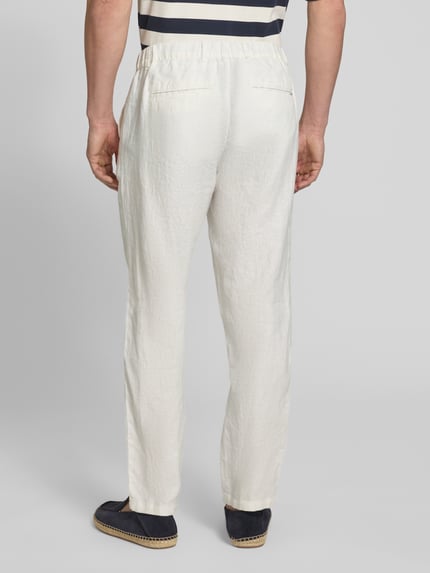 Männermodel trägt Leinenhose mit Eingrifftaschen Modell 'Pandrup' von Casual Friday in Offwhite, lockerer Schnitt, Ganzkörperansicht Rückansicht.