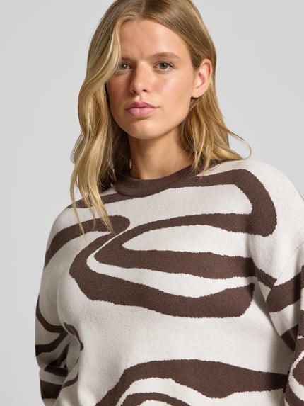 Kobiece modelka ma na sobie Relaxed Fit Pullover aus Viskose-Mix Modell 'Charlott' od NOISY MAY®, biały z brązowym animal-printem, długie rękawy, okrągły dekolt, prążkowane wykończenia, tekstura miękka, widoczny wzór, widok z przodu, zbliżenie na górną część ciała.