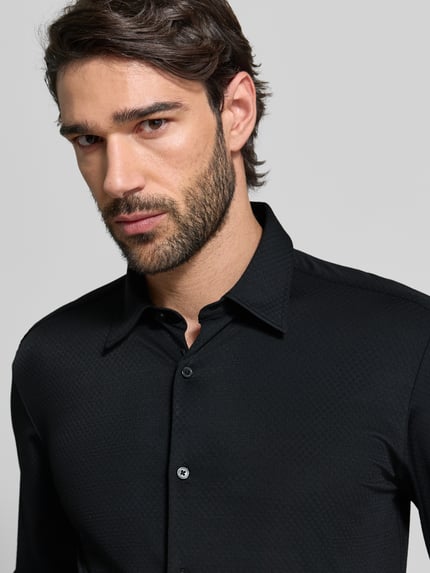 Männermodel trägt Slim Fit Business Hemd mit Kentkragen Modell 'ROAN' von BOSS, unifarbenes Schwarz, Stretch-Material, Nahaufnahme Oberkörper.