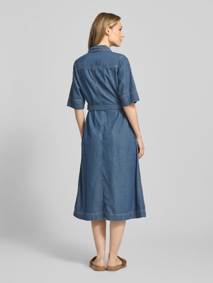 Vrouwenmodel draagt Fit and Flare Jeanskleid aus reiner Baumwolle van Tommy Hilfiger in denimlook, met riem, midilengte, korte mouw, borstzakken, zijsteekzakken, gestikt logo, knoopsluiting, puur katoen, geheelopname achteraan.