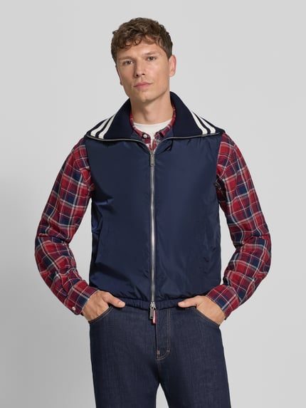 Männermodel trägt Weste mit Kontraststreifen von Dsquared2, dunkelblau mit weißem Kragen, Zweiwege-Reißverschluss, Ganzkörperansicht von vorne. Gerade Passform, elastischer Bund, Strukturmix mit glatter und gerippter Textur.