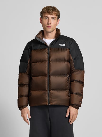 Männermodel trägt Regular Fit Jacke mit Daunen-Feder-Füllung Modell 'Diabolo' von The North Face in Braun und Schwarz, Stepp-Optik, Logo-Stitching, Stehkragen, Ganzkörperansicht von vorne. Rückenlänge 70 cm, Schulterbreite 47 cm, Brustweite 58 cm, Ärmellänge 69 cm.