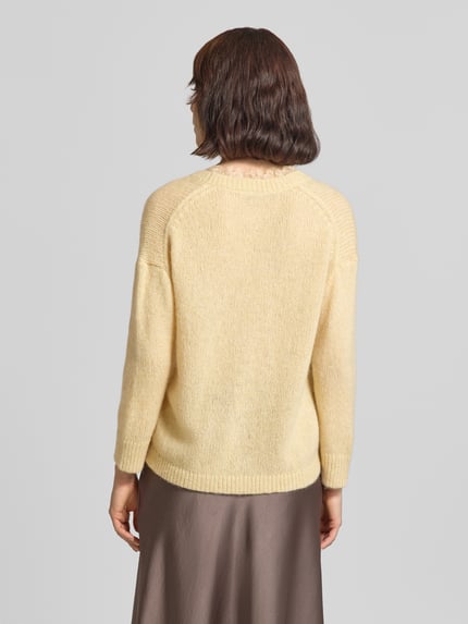 Frauenmodel trägt Strickjacke mit V-Ausschnitt und Spitzenbesatz von Luisa Cerano in hellem Gelb, Material-Mix mit Alpaka-Anteil, Relaxed Fit, Ganzkörperansicht Rückansicht.