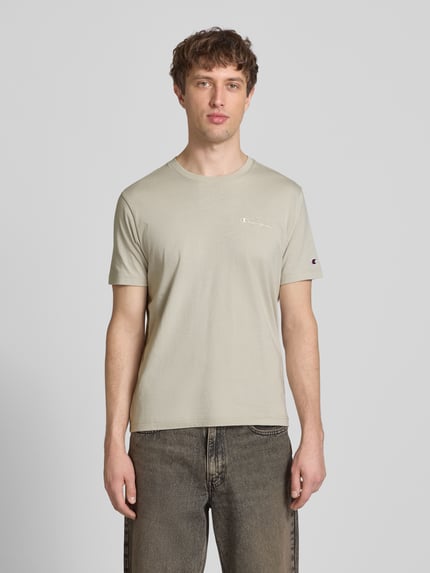 Männermodel trägt T-Shirt mit Label-Stitchings und Rundhalsausschnitt von CHAMPION aus Reine Baumwolle in Regular-Fit, Ganzkörperansicht von vorne, Rückenlänge bei Größe M: 69 cm.
