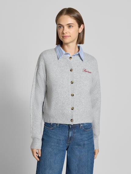 Frauenmodel trägt Strickjacke mit Label-Stitching von REVIEW in Grau, Ripp-Struktur, lockerer Schnitt, Ganzkörperansicht von vorne.