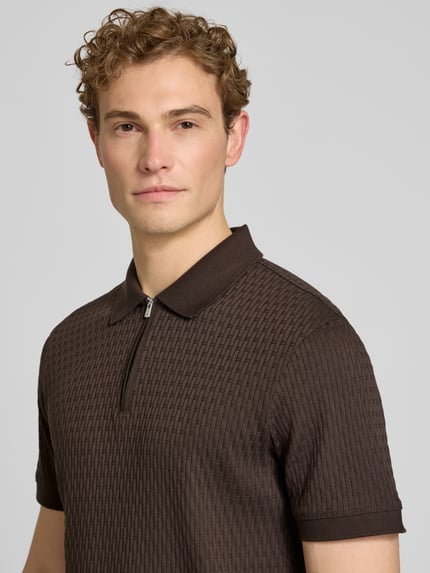 Mężczyznamodel nosi Slim Fit Poloshirt mit Reißverschluss Modell 'Franciscojose' od JOOP! Collection, czysta bawełna, krój slim fit, brązowy, teksturowana powierzchnia, kolekcja męska, kontekst: długość pleców w rozmiarze M 70 cm, półzbliżenie na górną część ciała.