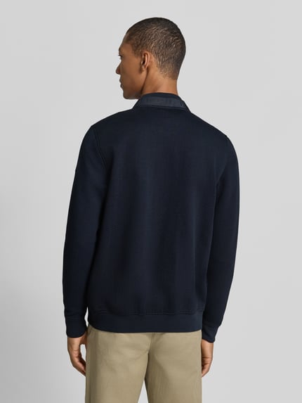 Męski model nosi Sweatjacke mit Reißverschluss od bugatti, bawełniana mieszanka, krój regular fit, wzór strukturalny, długość pleców w rozmiarze M: 58 cm, długość rękawa w rozmiarze M: 67 cm, kolor granatowy, widok całej sylwetki z tyłu.