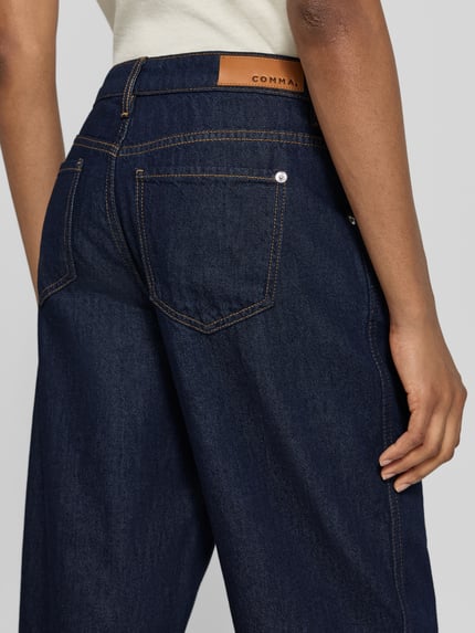 Frauenmodel trägt Straight Fit Jeans mit Knopfverschluss von COMMA aus Baumwoll-Lyocell-Mix in Dunkelblau, sichtbare Gesäßtaschen, Ganzkörperansicht Rückansicht.