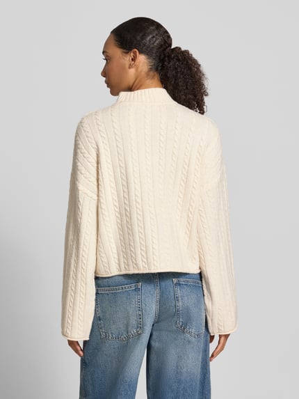 Vrouwenmodel draagt Relaxed Fit Strickpullover aus elastischem Material-Mix van REVIEW in crèmewit met kabelstructuur, Fledermausmouwen, col, rolzoom, detail van elastische mix, achterkant, Ganzkörperansicht Rückansicht.