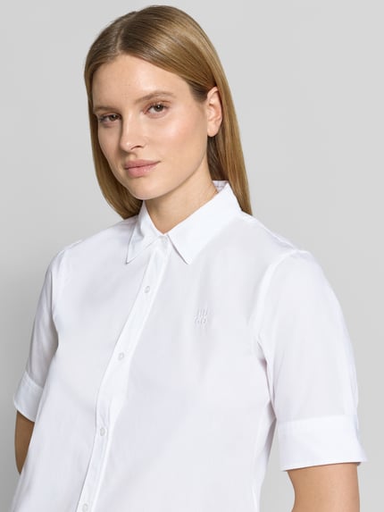 Kobiece model prezentuje bluzkę koszulową Oversized Hemdbluse aus reiner Baumwolle Modell 'The Summer Shirt' od HUGO, efekt: jednolity kolor, popelina, wyhaftowane logo, dekolt w serek, kołnierzyk koszulowy, krótki rękaw, zapięcie na guziki, wykończenie zaokrąglone, bawełna, zbliżenie na górną część ciała.