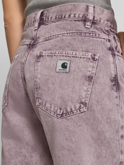 Frauenmodel trägt Straight Fit Jeansshorts im 5-Pocket-Design von Carhartt Work In Progress aus Reine Baumwolle, Bundweite 40 cm, Innenbeinlänge 26 cm, lila Batik-Optik, Nahaufnahme Rückansicht.