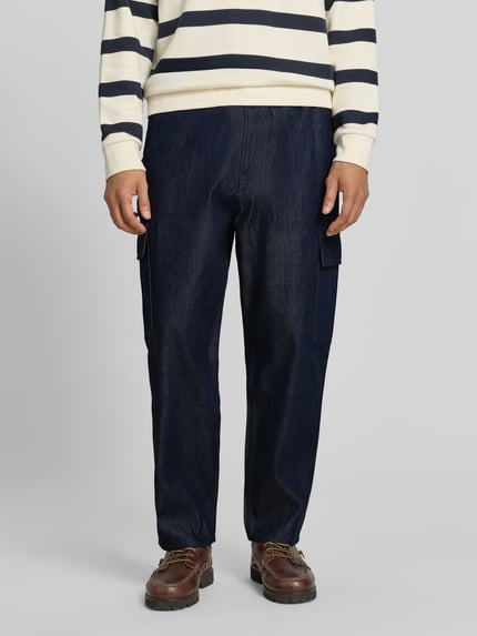 Männermodel trägt dunkelblaue Tapered Fit Jeans aus Baumwoll-Lyocell-Mix Modell 'Isak' von Marc O'Polo DENIM, Ganzkörperansicht von vorne.