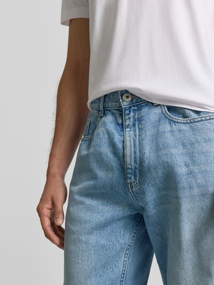 Männermodel trägt Baggy Jeans in heller Waschung und klassischem Five-Pocket-Design von REVIEW, reine Baumwolle, Nahaufnahme Oberkörper.