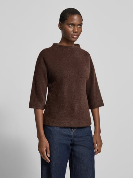 Kobiece modelka nosi sweter 'Pullover mit Stehkragen und 3/4-Arm' od zero, Mieszanka materiałów z dodatkiem streczu, krój regular fit, stójka, rękaw o dł. 3/4, ciemnobrązowy, faktura miękka, widoczny przód, ujęcie całej sylwetki z przodu.