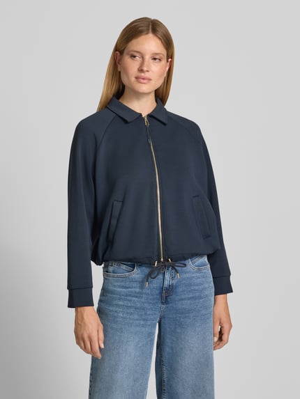 Frauenmodel trägt Sweatjacke mit Zweiwege-Reißverschluss Modell 'Taimi' von JOOP! in Dunkelblau, Material-Mix, Umlegekragen, Relaxed Fit, Eingrifftaschen, Tunnelzug, Ganzkörperansicht von vorne.