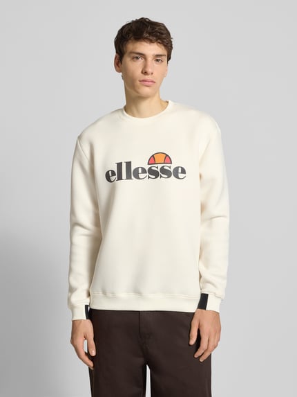 Męski model nosi Sweatshirt mit Label-Print Modell 'CORVARO' od Ellesse, kremowy kolor, luźny krój, materiał z domieszką wiskozy, widok z przodu, ujęcie całej sylwetki.