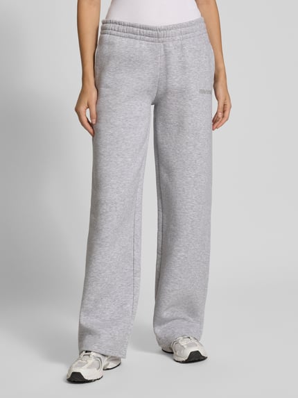 Frauenmodel trägt Sweathose in grau melange mit geradem Bein von REVIEW, Baumwoll-Mix, elastischer Bund, Ganzkörperansicht von vorne.