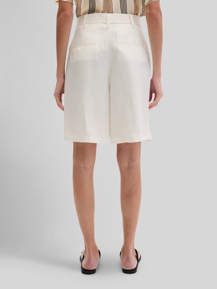 Frauenmodel trägt Relaxed Fit Shorts mit Leinen-Anteil von Marc O'Polo, Optik: Unifarben, Passform: Relaxed-Fit, High-Waist, Bundfalten, Stoffgürtel, Knopf und verdeckter Reißverschluss, strukturierter Stoff, dezente Taschen, Ganzkörperansicht Rückansicht.