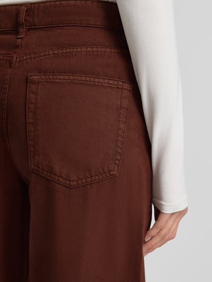 Frauenmodel trägt Loose Fit Jeans mit 5-Pocket-Design Modell 'CAROL' von Mango in Braun, Reine Baumwolle, lockerer Schnitt, Detailaufnahme Rückansicht.