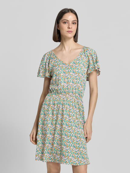 Vrouwenmodel draagt mini-jurk van viscosemix met getailleerde pasvorm, bloemen all-over print, korte mouw, V-hals, model 'Aya' van ICHI, ruglengte maat 36: 89 cm, borstwijdte: 48 cm, mouwlengte: 23 cm, kleurenmix met kleine bloemenmotieven, soepelvallende stof, Ganzkörperaanzicht van voren.