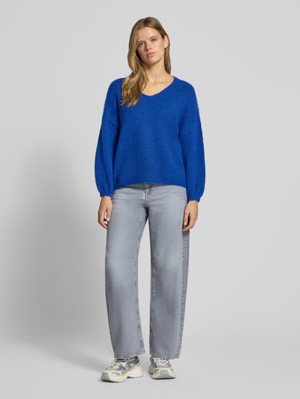 Frauenmodel trägt Pullover mit V-Ausschnitt Modell 'PCALLIE' von PIECES in blauer Melange-Optik, Strick, Ganzkörperansicht von vorne.