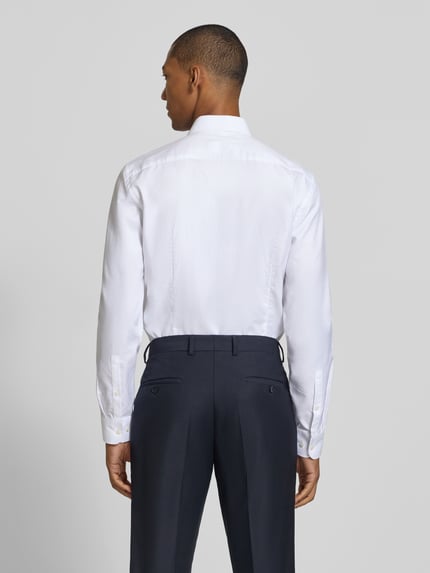 Männermodel trägt weißes Slim Fit Businesshemd mit extra langem Arm von Jake*s, glatte Textur, klassische Knopfleiste, Ganzkörperansicht Rückansicht.