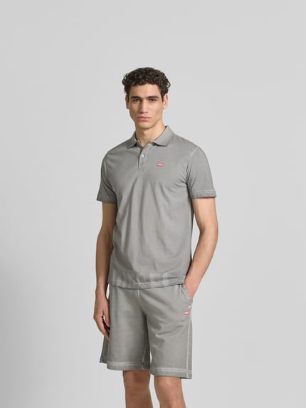 Męski model nosi Regular Fit Poloshirt aus Baumwolle von Diesel, szary, z krótkim rękawem, logo, kołnierzyk polo, krój regular fit, długość tyłu w rozmiarze M: 70 cm, bawełna, Ganzkörperansicht von vorne.